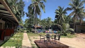 A tropical resort with palm trees, a wooden deck with chairs, and a pathway leading to a building. - Moonshine Resort Chumphon (Chumphon)
