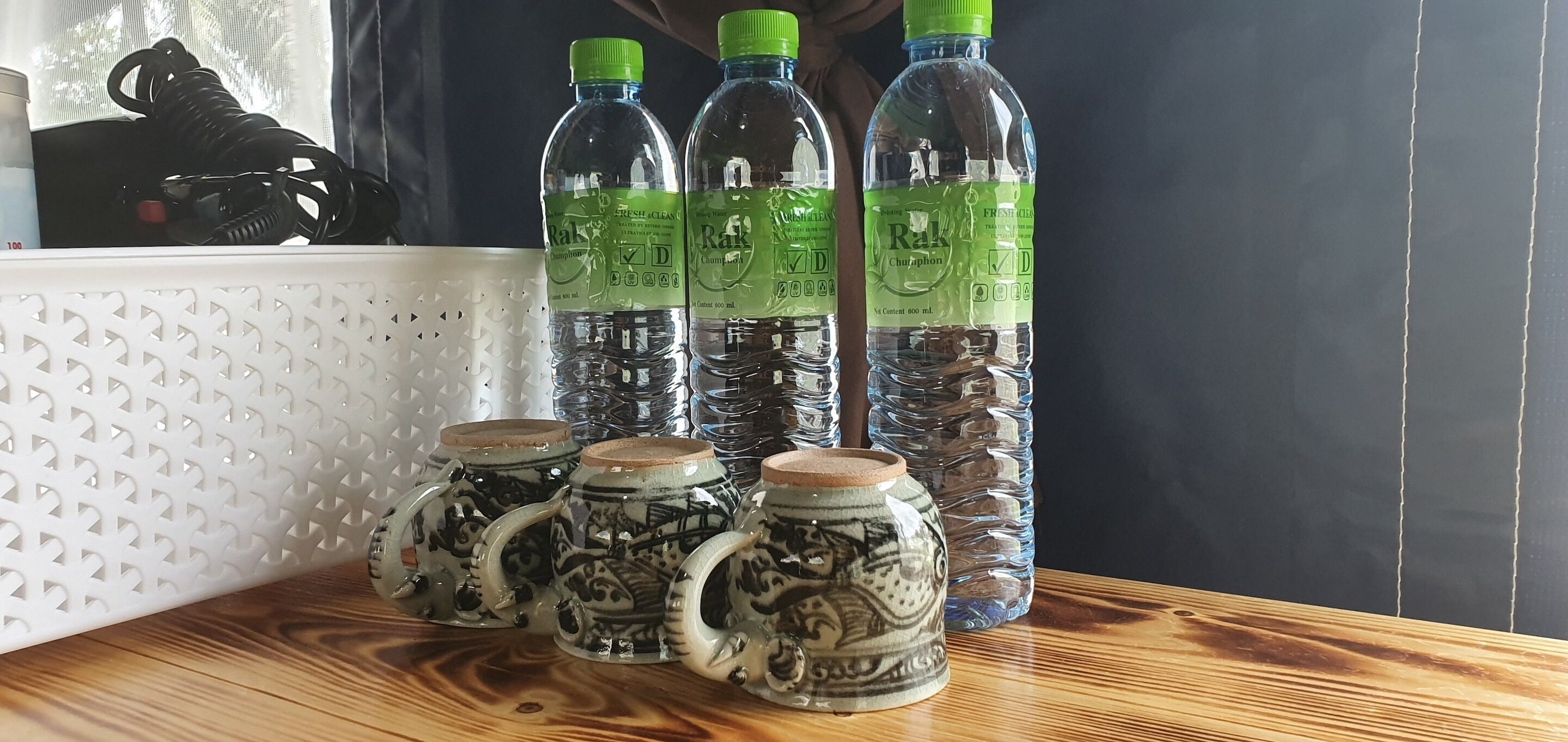 A table with four bottles of water and four ceramic mugs with intricate designs.