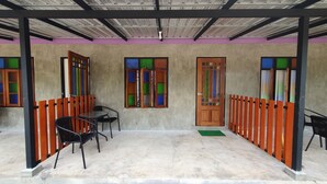 A covered outdoor seating area with tables and chairs, a wooden door, and colorful window panes. - Moonshine Resort Chumphon (Chumphon)