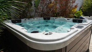 A hot tub with a control panel, surrounded by lush greenery.