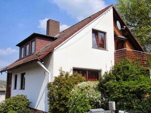 A two-story house with a sloped roof, a chimney, and a satellite dish. - Haus Tannenweg (Niestetal)