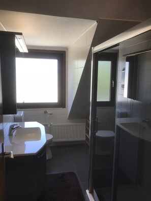 A modern bathroom with a large window, a shower, and a toilet. - Haus Tannenweg (Niestetal)