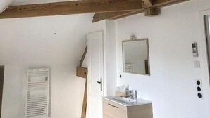 A room with exposed wooden beams, a white door, a mirror, and a sink. - Iris - Bed and breakfast (Ognes)