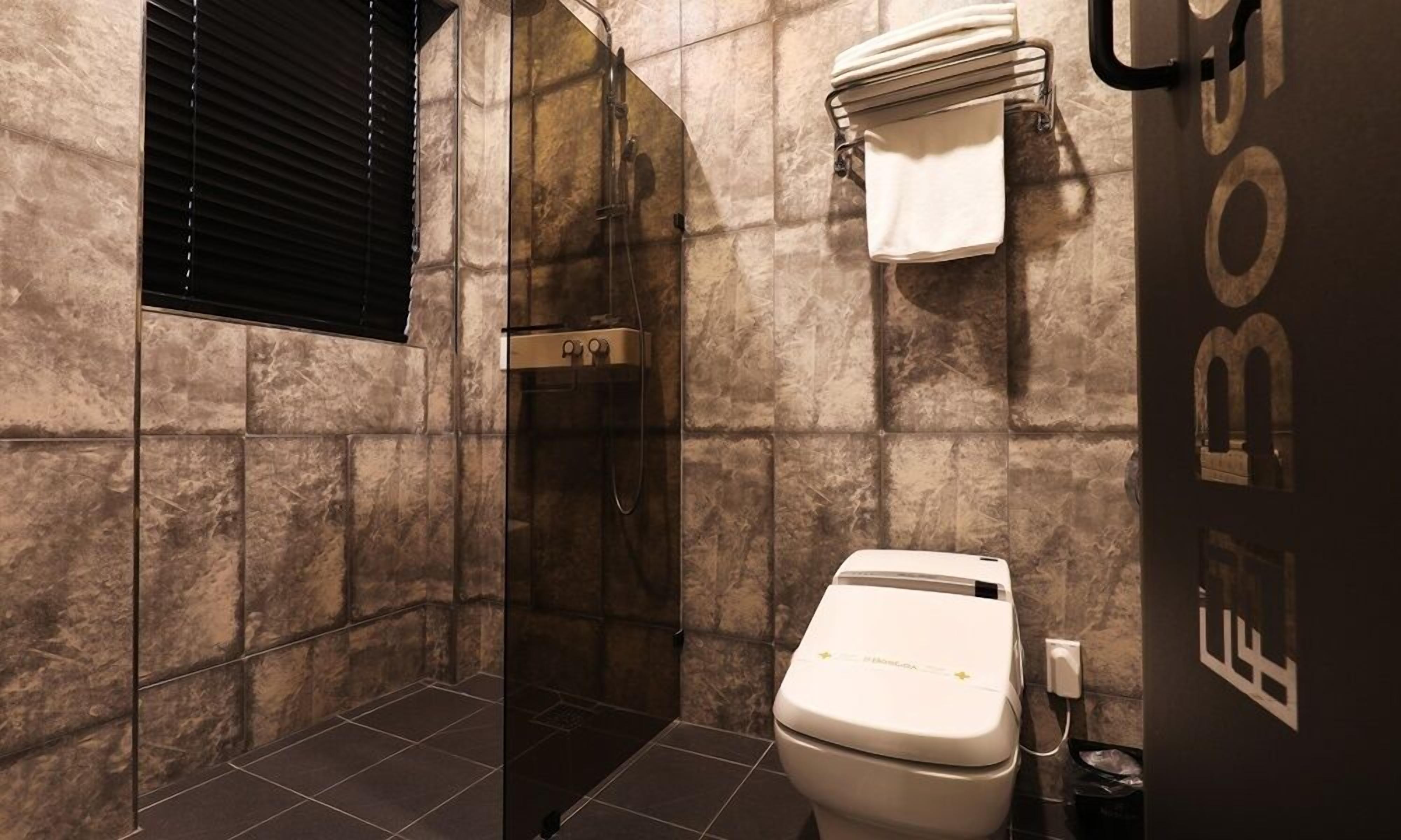 Un baño con ducha, inodoro y perchero para toallas.