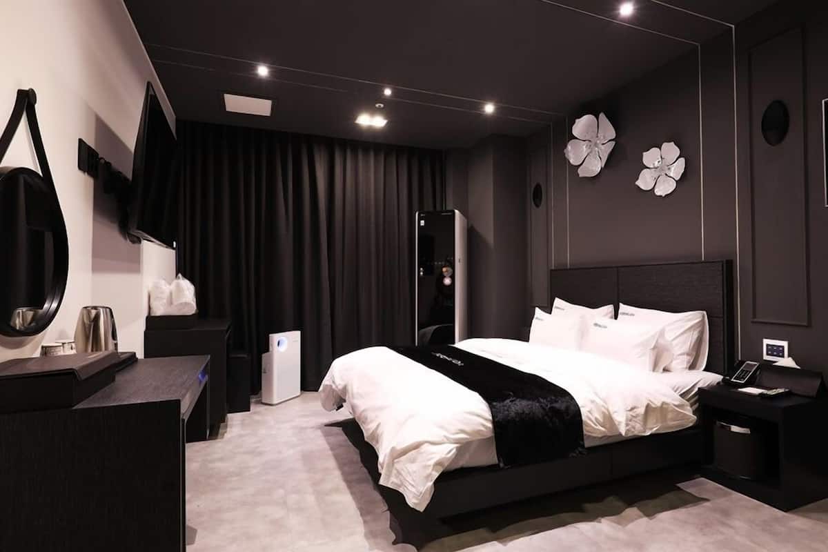 Un dormitorio moderno con una cama grande, mesitas de noche, un espejo y un armario.