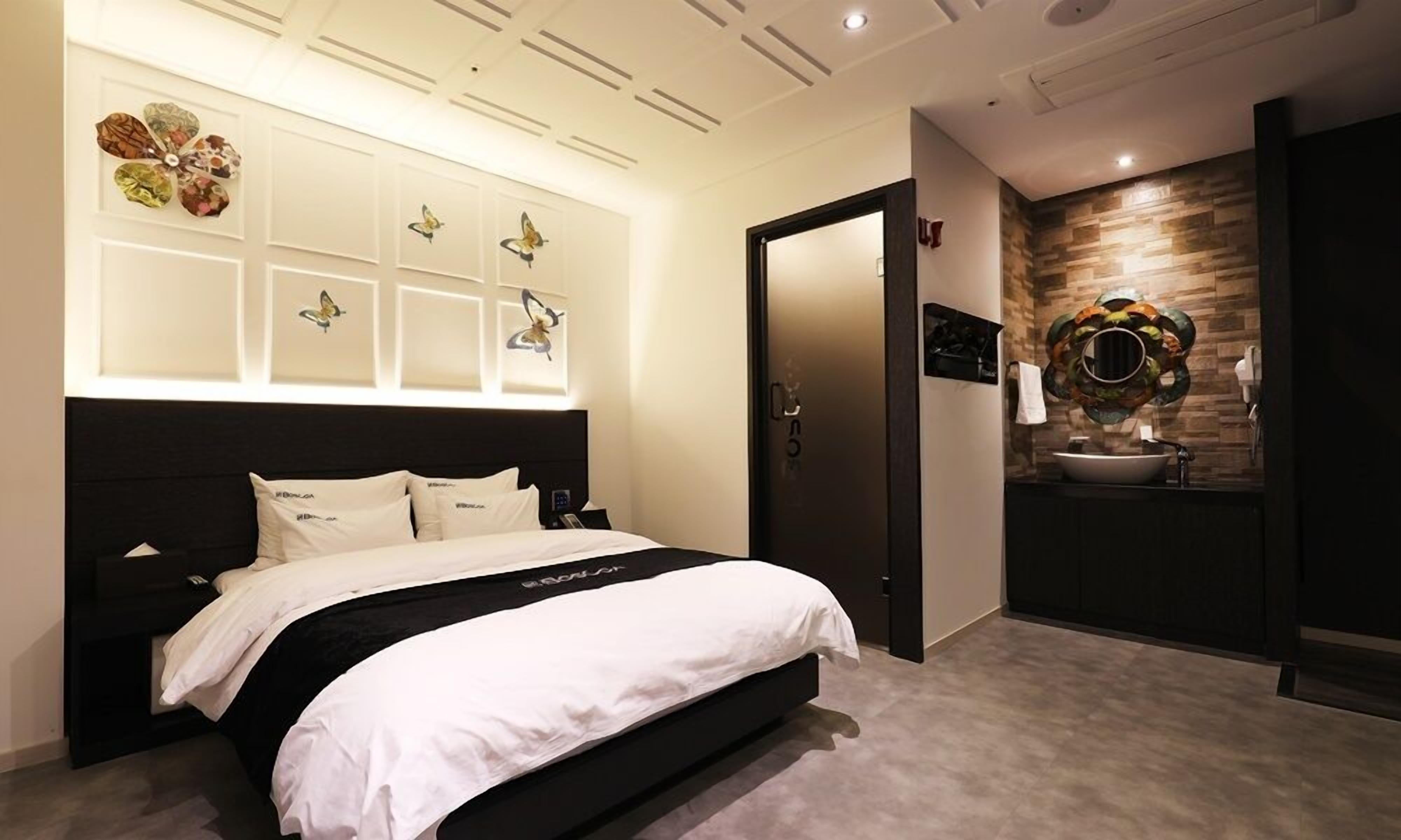 A modern bedroom with a bed, a bathroom with a sink, and decorative wall art.