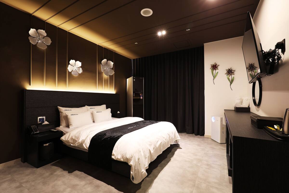Una habitación de hotel moderna con una cama grande, mesitas de noche, un escritorio y un televisor montado en la pared.