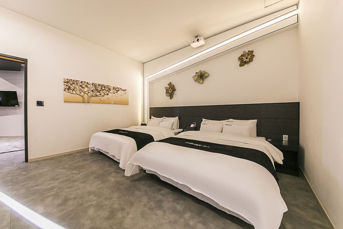 Habitación de hotel con dos camas, diseño moderno, televisor de pantalla plana y una obra de arte en la pared.