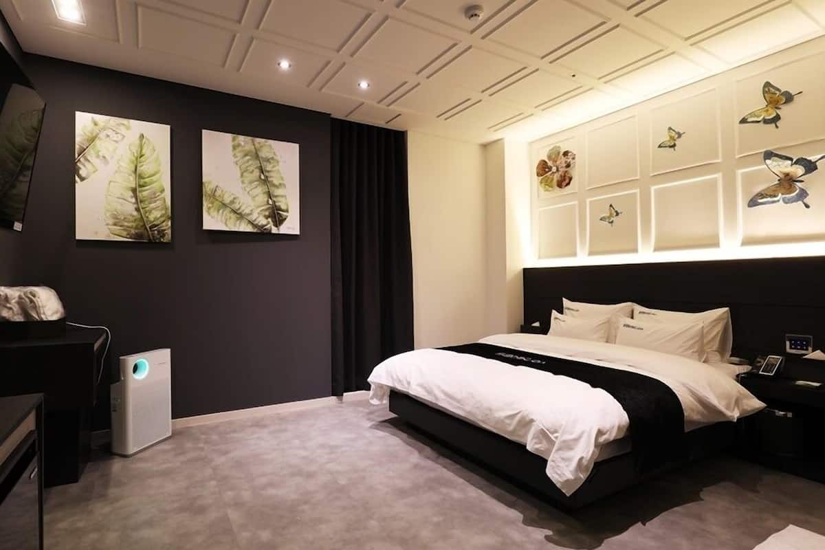 Un dormitorio moderno con cama, mesitas de noche, un escritorio y obras de arte en las paredes.