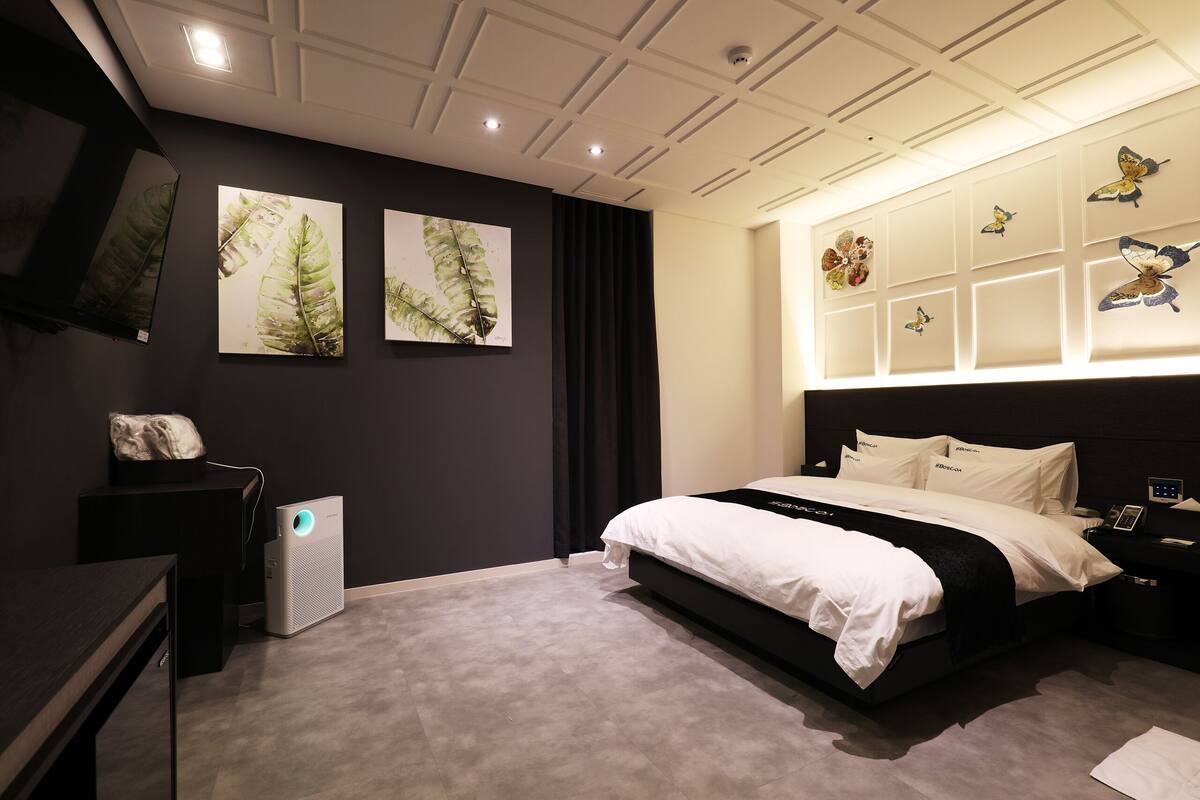 Un dormitorio moderno con una cama grande, un televisor de pantalla plana y obras de arte en las paredes.