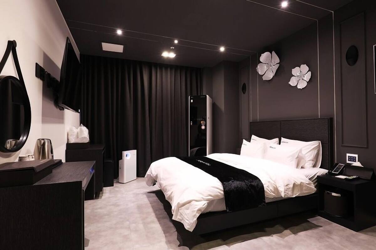 Un dormitorio moderno con una cama grande, mesitas de noche, un espejo y un armario.