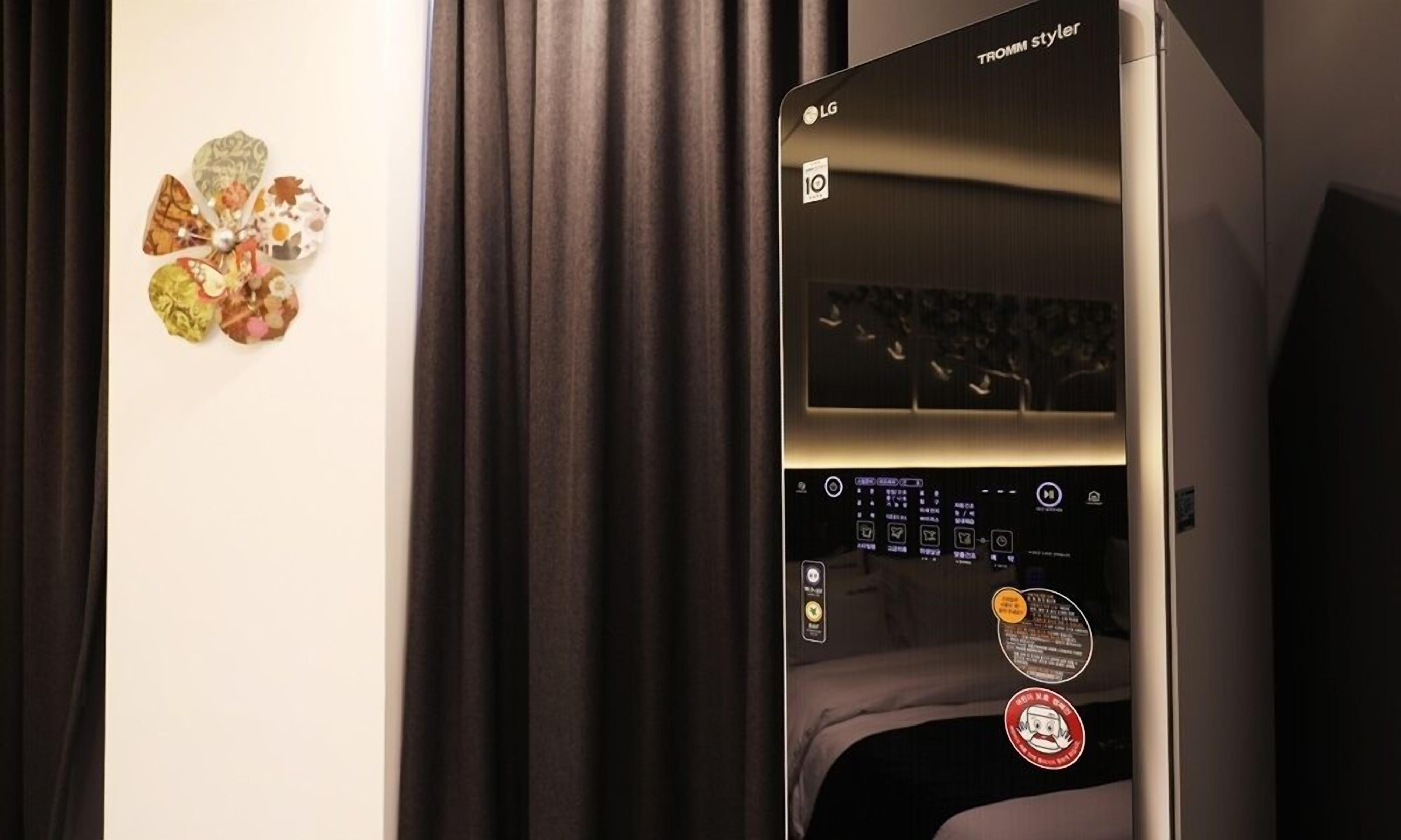 A room with a bed, a wall-mounted TV, and a curtain.