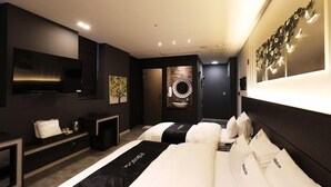 A modern hotel room with a large bed, a flat-screen TV, a small seating area, and a decorative wall piece. - Wonju Boscoa Hotel (Wonju)