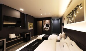 A modern hotel room with a large bed, a flat-screen TV, a small seating area, and a decorative wall piece. - Wonju Boscoa Hotel (Wonju)