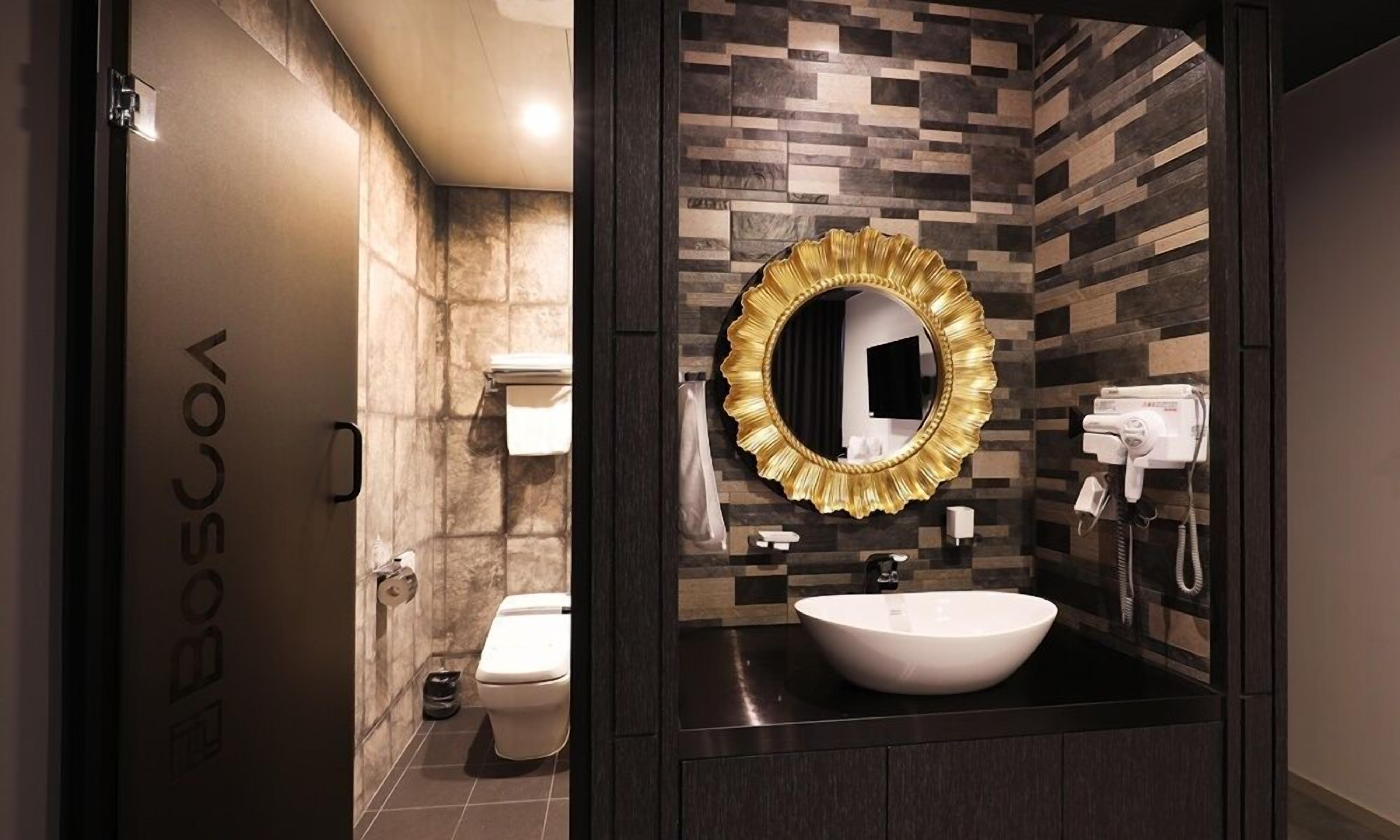 A modern bathroom with a large mirror, a sink, and a toilet.