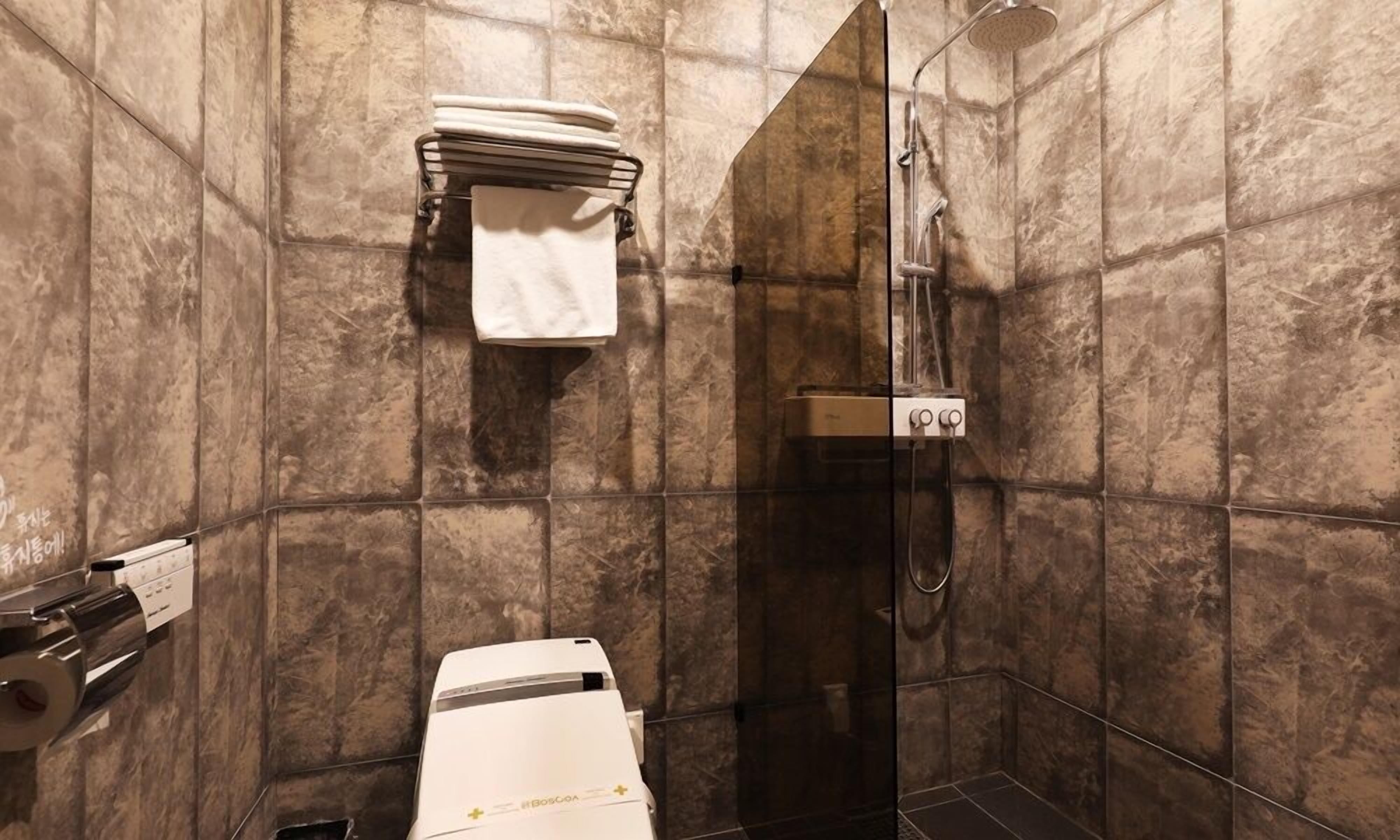 A bathroom with a shower, a towel rack, and a toilet.