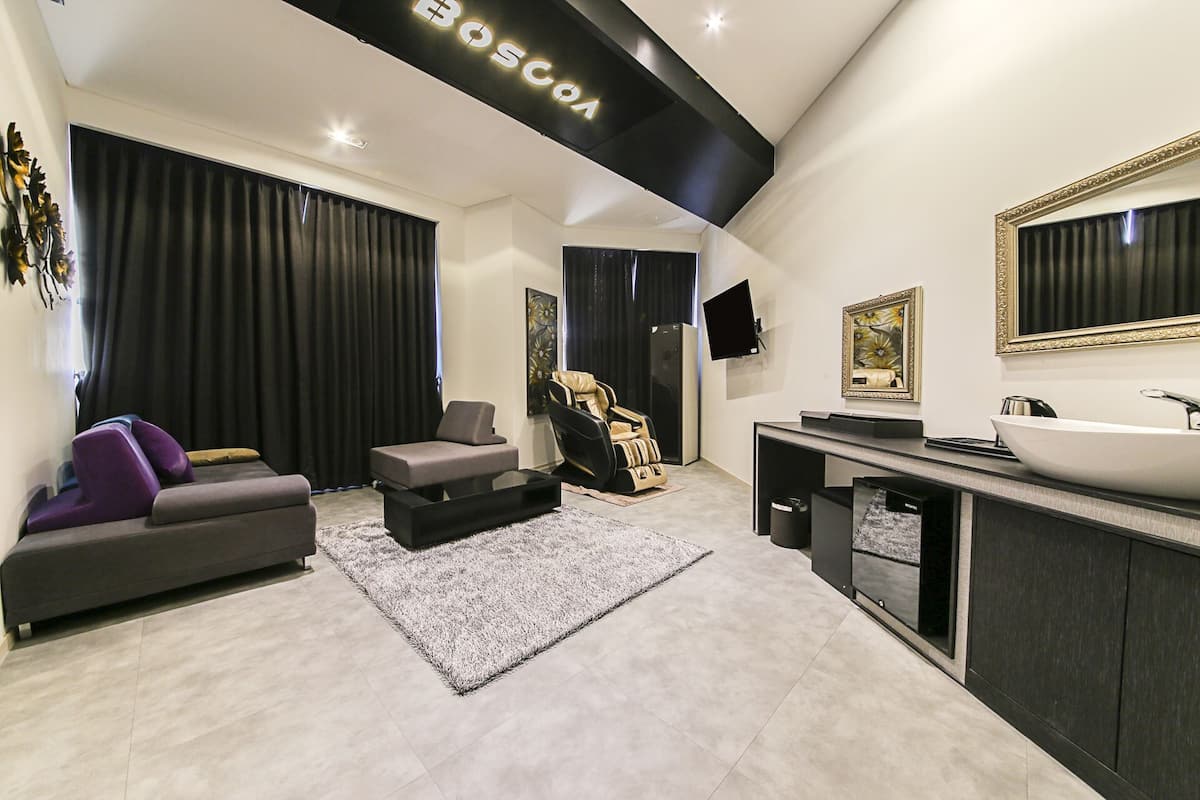 Una sala de estar moderna con un sofá, un sillón de masaje, un televisor de pantalla plana y un espejo grande.