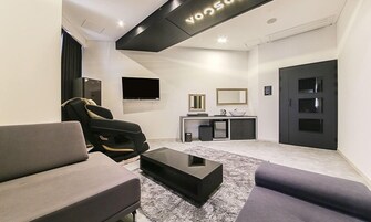 Una sala de estar moderna con un sofá, un sillón reclinable, una mesa de centro, un televisor de pantalla plana, un espejo y una puerta.