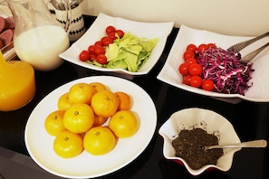 Una mesa con diferentes alimentos, incluyendo naranjas, lechuga, tomates cherry y repollo rallado.