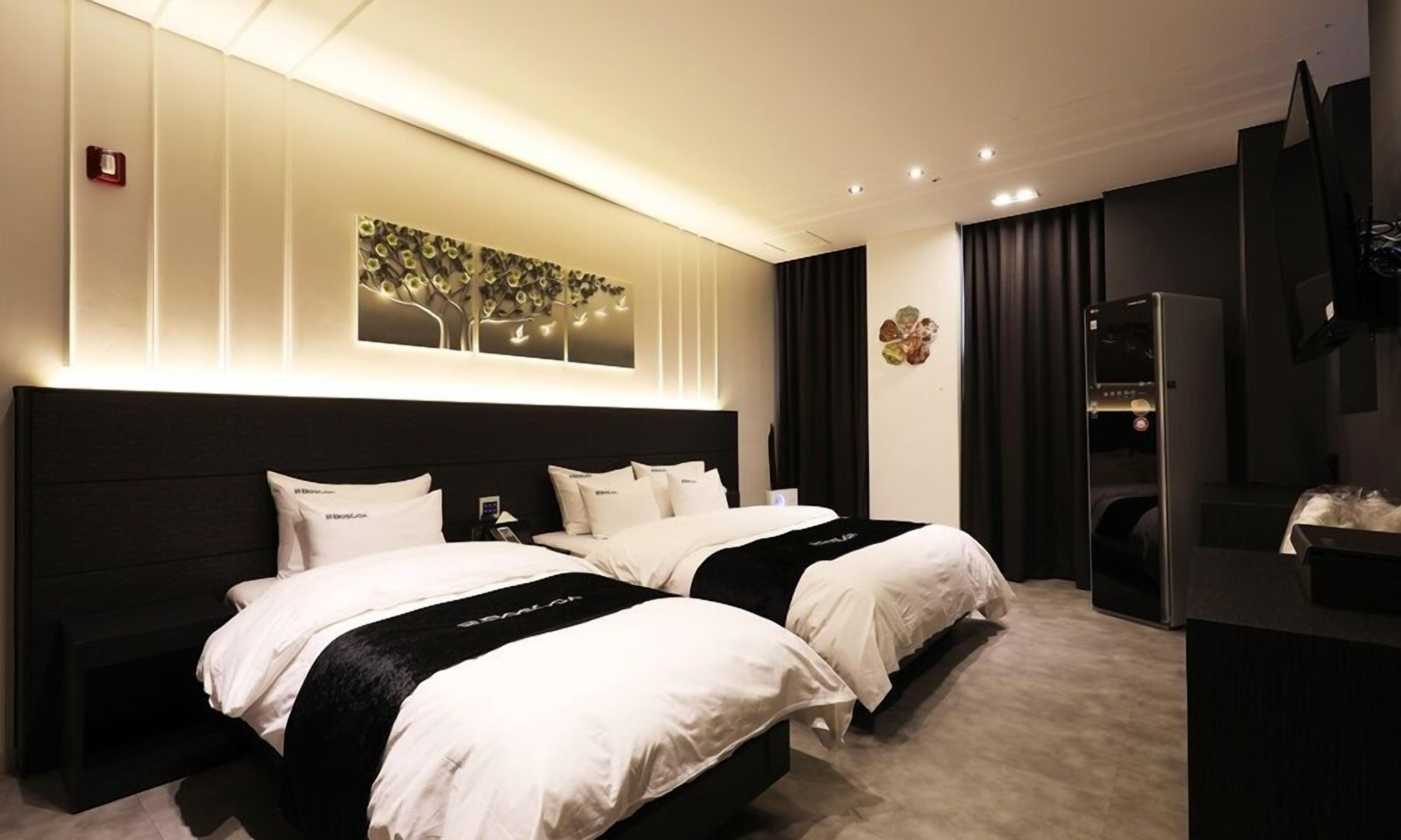 Habitación de hotel con dos camas, una obra de arte grande en la pared, un televisor de pantalla plana y un minibar.