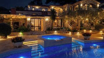 A luxurious property with a swimming pool, outdoor seating, and a well-lit patio area.