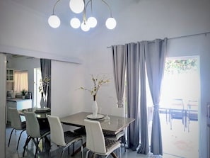 A modern dining area with a glass table, white chairs, and a vase with flowers.