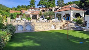 A large estate with multiple buildings, a stone wall, and a well-maintained lawn.