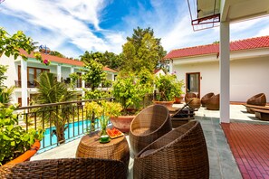 Une terrasse sur le toit, aménagée avec des meubles en osier, une piscine et des plantes en pot.
