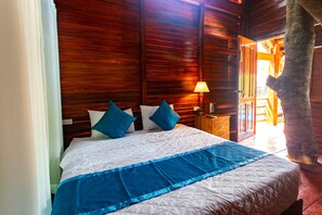 Un lit recouvert d’une couvre-lit bleue et blanche, des murs en bois et une table de chevet avec une lampe.