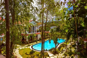 Une piscine entourée d’un jardin agrémenté de palmiers et d’un sentier.