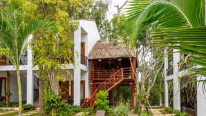 A building with a thatched-roof structure, surrounded by lush greenery and a well-maintained garden with stone pathways and lounge chairs. - Caesar Phu Quoc Hotel (Phu Quoc)