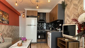 Une cuisine compacte dotée d’appareils électroménagers modernes, un coin repas avec une table en marbre et un salon agrémenté d’un canapé et d’objets décoratifs.