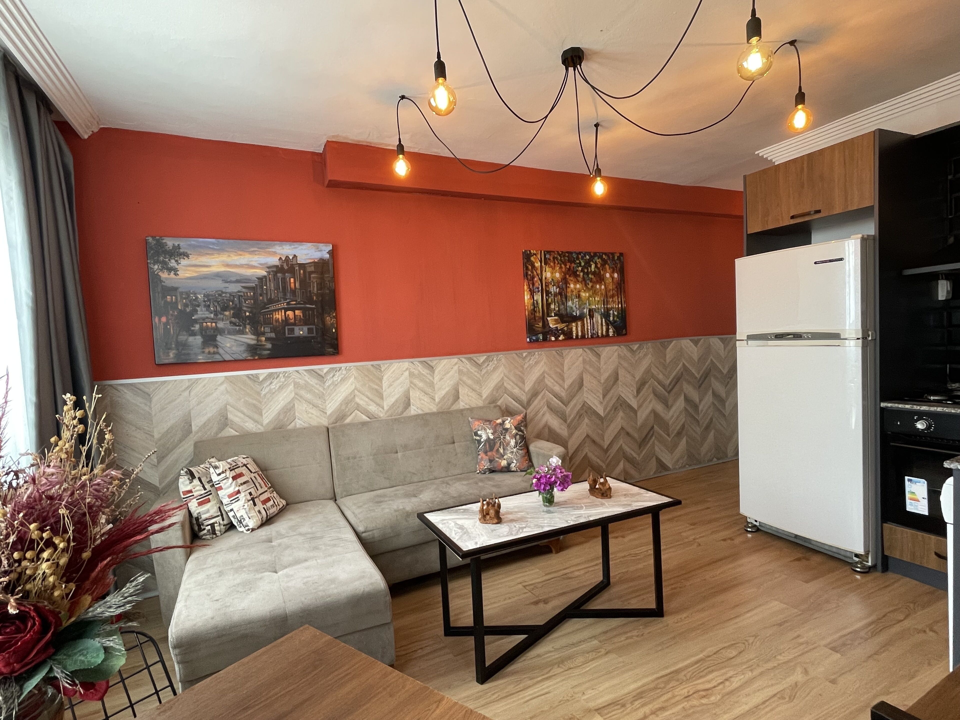 A modern living room with a sofa, a coffee table, and a kitchen area with a refrigerator.