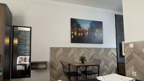 Une chambre d’hôtel moderne avec un grand lit, un coin repas, un tableau et un miroir.