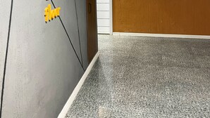 Un couloir avec un mur gris orné de texte et de chiffres jaunes, une porte en bois et un tableau représentant des oiseaux.