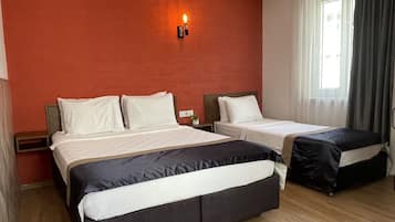 Ein Hotelzimmer mit zwei Betten, einem Nachttisch, einer Wandlampe und einem Fenster mit Vorhängen.