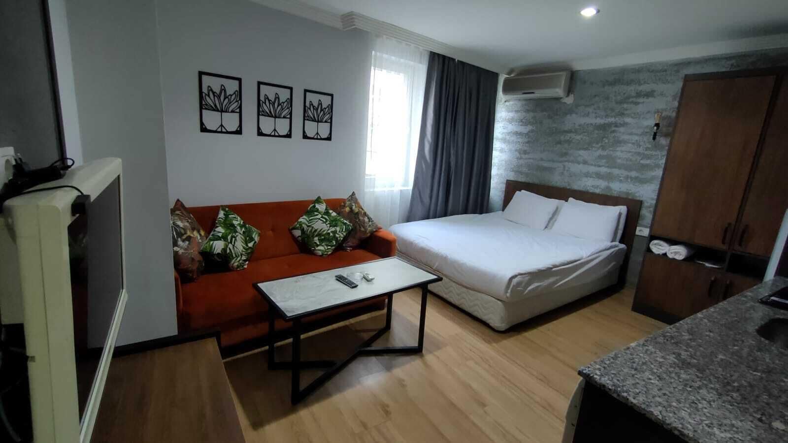 A hotel room with a bed, a sofa, a coffee table, and a kitchenette.