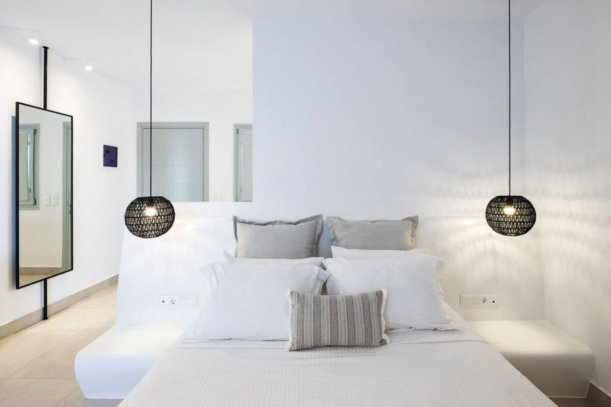 A modern bedroom with a large bed, two bedside lamps, and a mirror on the wall.