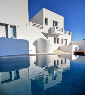 Un bâtiment moderne dont l’architecture se reflète dans une piscine.