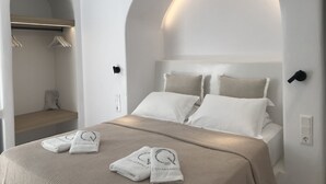 Ein modernes Hotelzimmer mit Bett, zwei Kissen, Nachttisch und Garderobe.