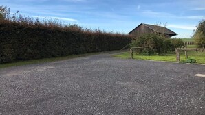 A gravel driveway leading to a wooden barn with a metal gate. - Studio le Charme d'Ognes (Ognes)