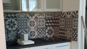 A kitchen with white cabinets and patterned backsplash tiles. - Studio le Charme d'Ognes (Ognes)