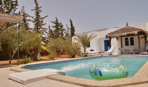 A swimming pool with lounge chairs and a water feature.