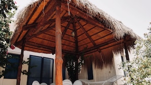 A covered outdoor seating area with a thatched roof, white plastic chairs, and a table. - 'DAR Leyla' CHARMING VILLA WITH POOL.... AT THE HEART OF THE DJERBIAN CAMPAIGN (Mezraya)