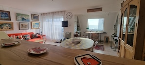 Una sala de estar acogedora con una mesa de comedor de madera, un sofá rojo y un televisor montado en la pared.