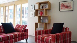 A living room with two plaid sofas, a wooden bookshelf, and a framed picture on the wall. - Chalet Bella Vista 1 (Lauterbrunnen)