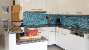 A modern kitchen with white cabinets, a blue mosaic backsplash, and stainless steel appliances. - Chalet Bella Vista 1 (Lauterbrunnen)