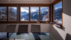 A conference room with a glass table, four chairs, and a view of snow-covered mountains through large windows. - Chalet Dillon (Lauterbrunnen)