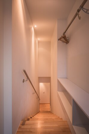 A narrow staircase with wooden steps and metal handrails, leading to a room with white walls and a wooden floor. - Chalet Dillon (Lauterbrunnen)
