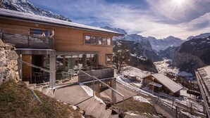 A modern two-story building with a balcony overlooking a snowy mountain valley. - Chalet Dillon (Lauterbrunnen)